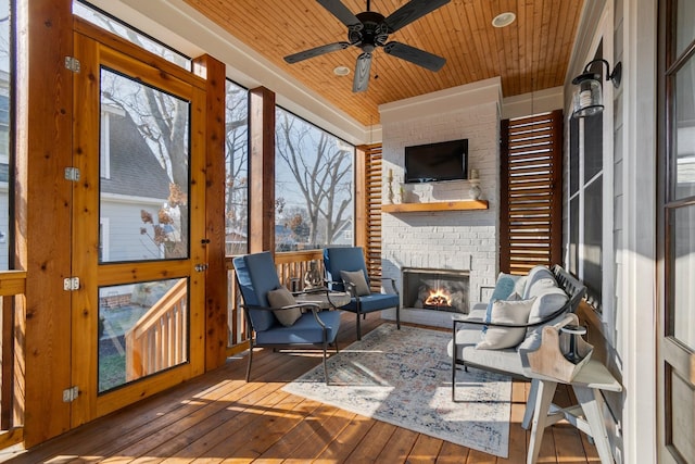 sunroom featuring wood ceiling, ceiling fan, and an outdoor brick fireplace