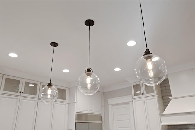 room details featuring white cabinetry, fridge, ornamental molding, and hanging light fixtures