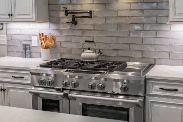 kitchen featuring white cabinetry, high end range, and backsplash