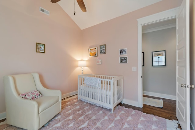 bedroom with lofted ceiling, a nursery area, ceiling fan, and light wood-type flooring