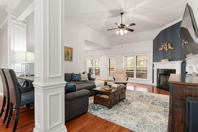 living room with hardwood / wood-style floors, lofted ceiling, ceiling fan, a fireplace, and decorative columns