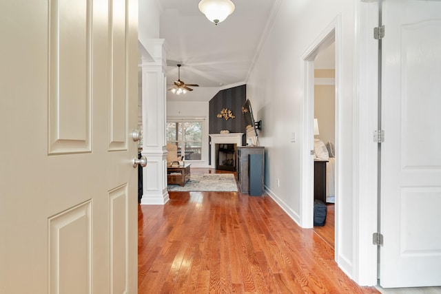 foyer featuring ornate columns, ceiling fan, crown molding, vaulted ceiling, and light wood-type flooring