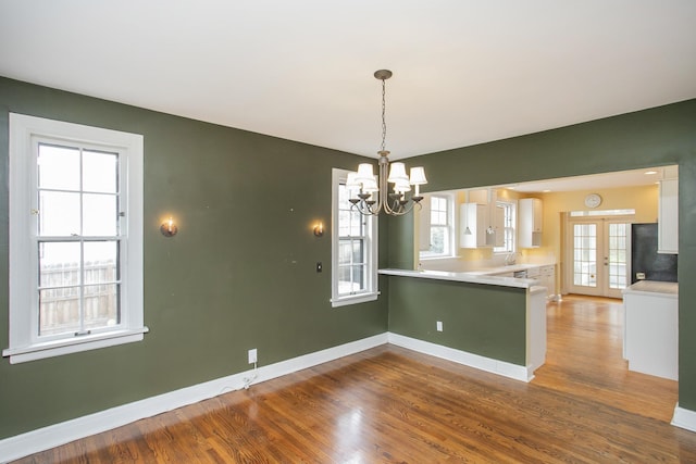 interior space with white cabinets, decorative light fixtures, a healthy amount of sunlight, and kitchen peninsula