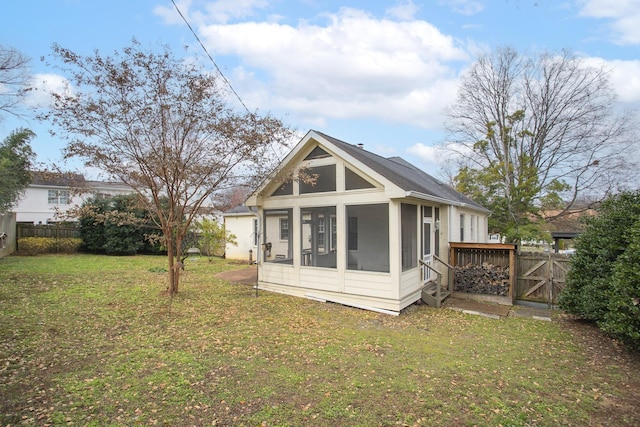 rear view of property with a lawn and a sunroom