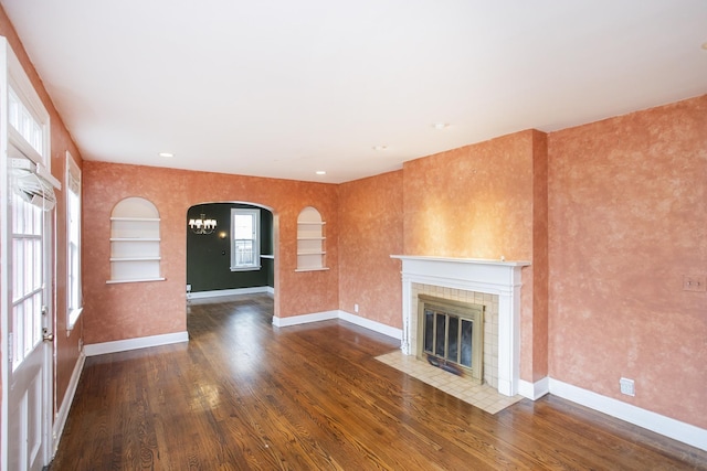 unfurnished living room with wood-type flooring and a tiled fireplace