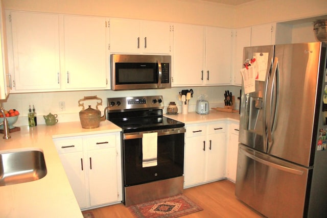 kitchen featuring white cabinetry, stainless steel appliances, and light wood-type flooring