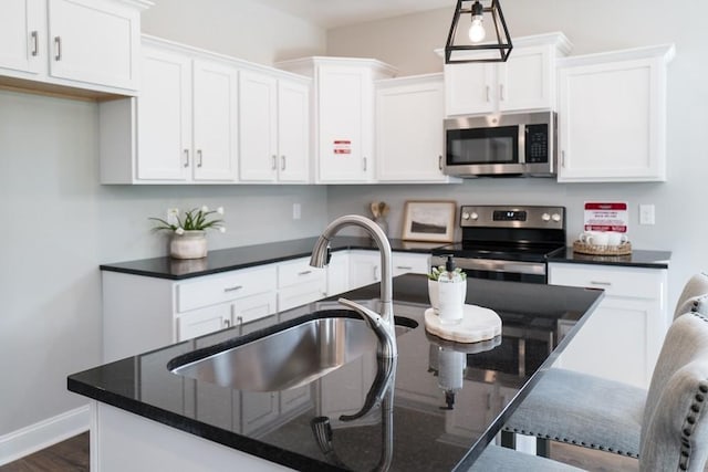 kitchen with white cabinetry, sink, dark wood-type flooring, hanging light fixtures, and appliances with stainless steel finishes