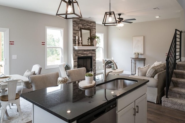 kitchen featuring white cabinets, sink, hanging light fixtures, dark hardwood / wood-style floors, and an island with sink