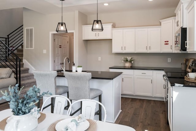 kitchen featuring white cabinets, a breakfast bar, dark hardwood / wood-style flooring, and hanging light fixtures