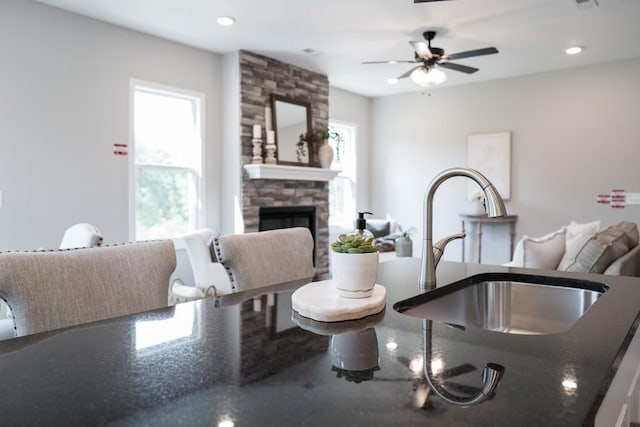 interior space featuring a fireplace, ceiling fan, a wealth of natural light, and sink