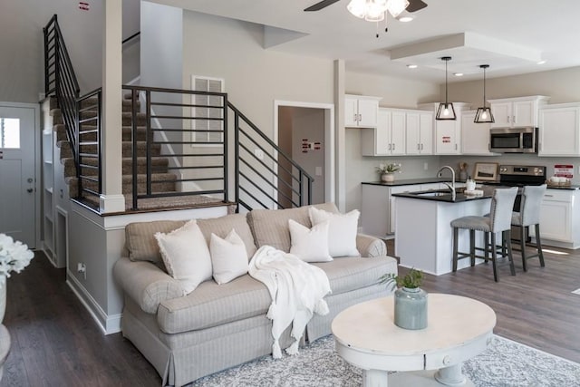 living room with dark hardwood / wood-style floors, ceiling fan, and sink