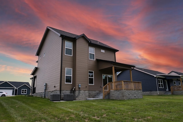 back house at dusk with central AC and a yard