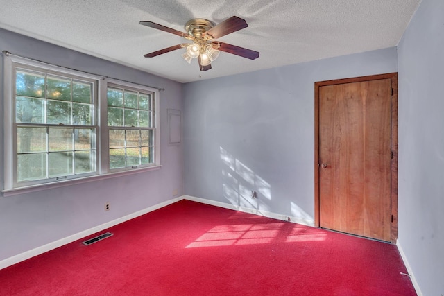 carpeted spare room with a textured ceiling and ceiling fan