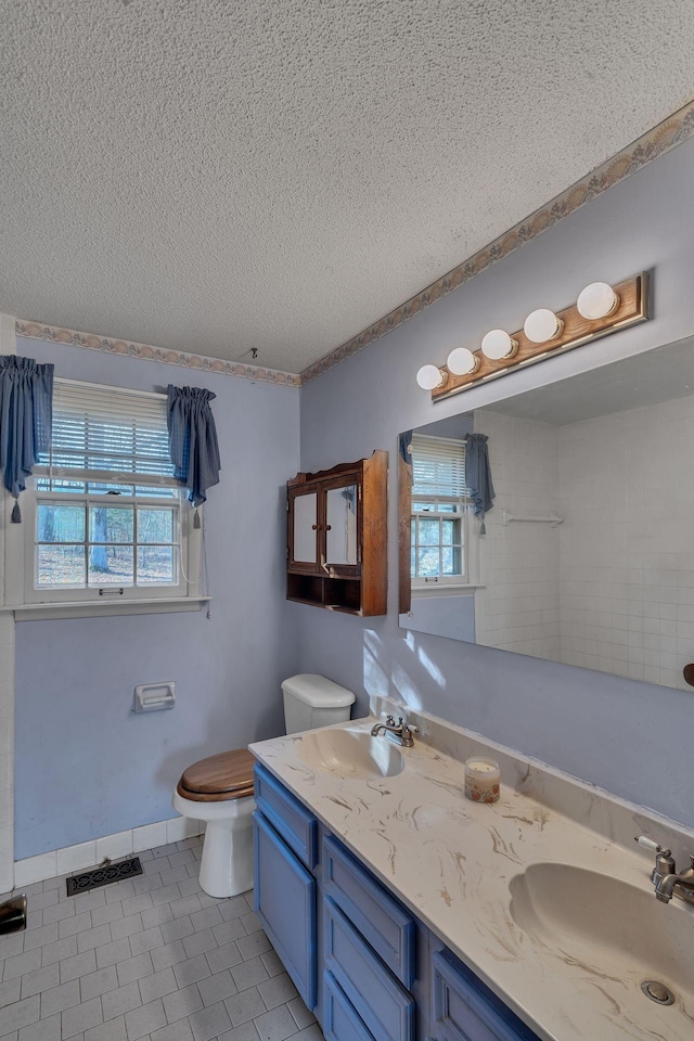 bathroom featuring tile patterned floors, vanity, a textured ceiling, and toilet