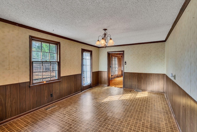 spare room with a chandelier, a textured ceiling, and ornamental molding