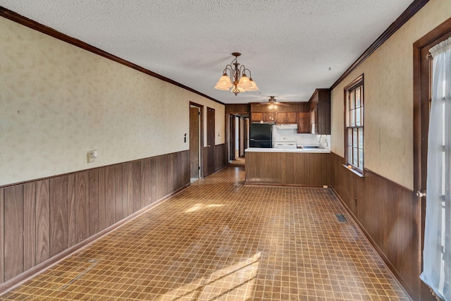 kitchen featuring an inviting chandelier, kitchen peninsula, pendant lighting, fridge, and ornamental molding