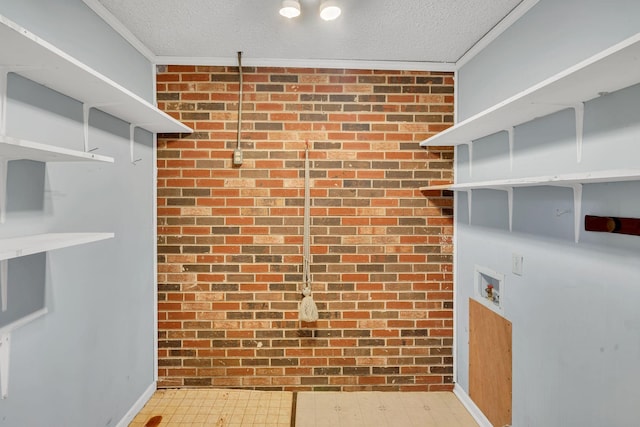 interior space with ornamental molding, a textured ceiling, and brick wall