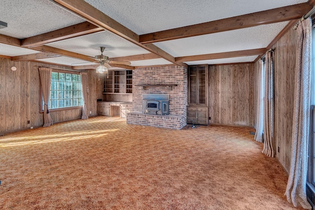 unfurnished living room with a textured ceiling, a wood stove, and wooden walls