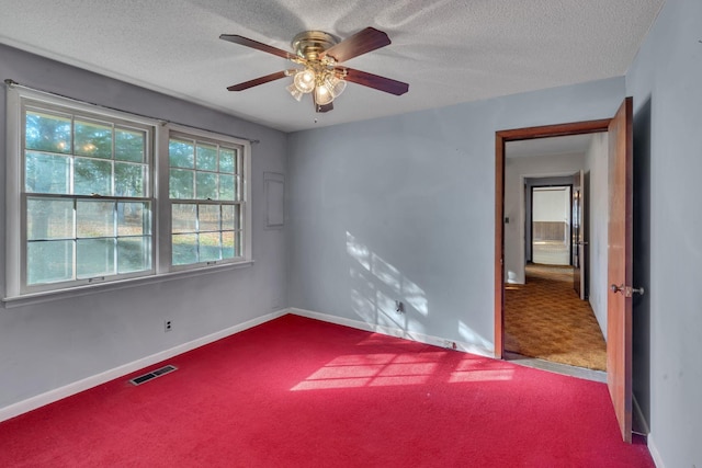 carpeted empty room with ceiling fan and a textured ceiling