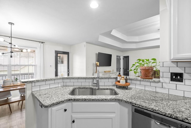 kitchen with white cabinetry, dishwasher, sink, light hardwood / wood-style flooring, and decorative backsplash