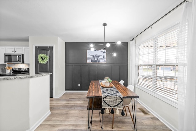 dining space with plenty of natural light, a chandelier, and light wood-type flooring