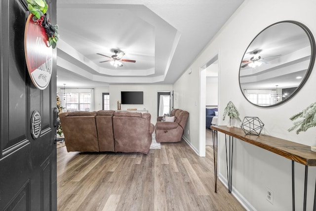 living room featuring a tray ceiling, light hardwood / wood-style flooring, and a notable chandelier