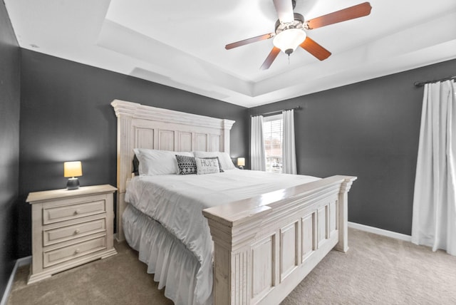 bedroom with a tray ceiling, ceiling fan, and light colored carpet