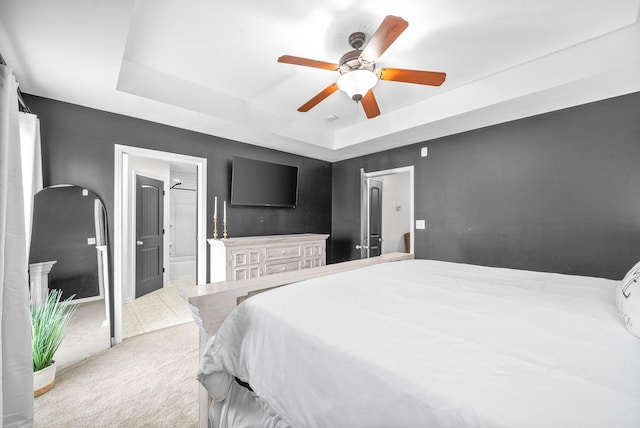 carpeted bedroom featuring ensuite bath, a raised ceiling, and ceiling fan