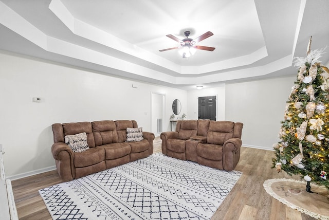 living room featuring a tray ceiling, ceiling fan, and hardwood / wood-style floors