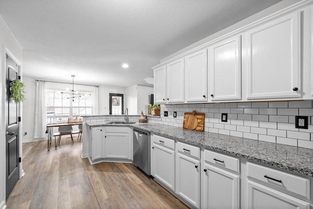 kitchen with kitchen peninsula, stainless steel dishwasher, sink, light hardwood / wood-style flooring, and white cabinets