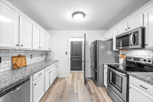 kitchen featuring light stone countertops, light hardwood / wood-style flooring, white cabinets, and appliances with stainless steel finishes