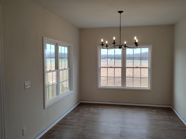 unfurnished dining area featuring a notable chandelier, a water view, and dark wood-type flooring