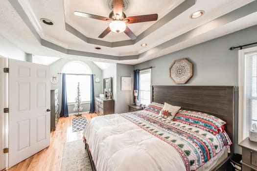 bedroom with crown molding, ceiling fan, a tray ceiling, and light wood-type flooring