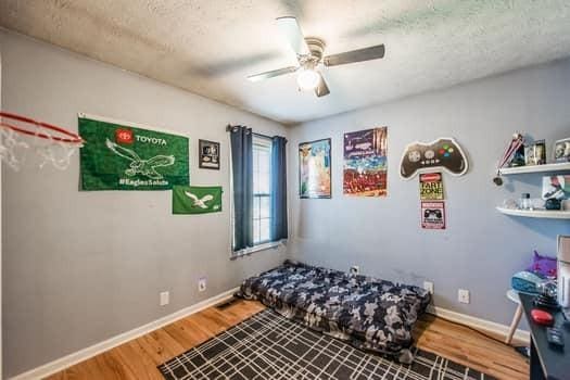 bedroom with hardwood / wood-style floors, a textured ceiling, and ceiling fan