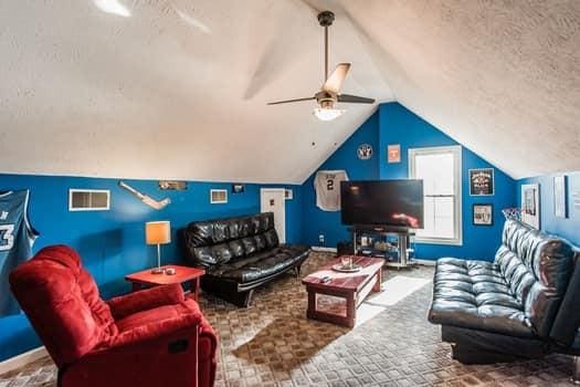 living room featuring lofted ceiling, carpet flooring, a textured ceiling, and ceiling fan