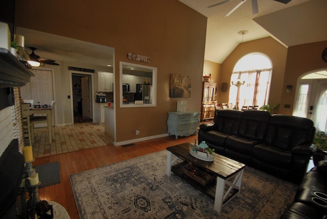 living room featuring lofted ceiling, wood-type flooring, a fireplace, and ceiling fan