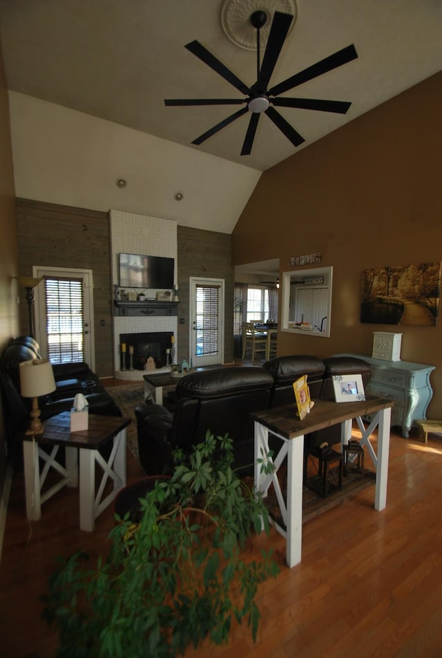 living room with a fireplace, vaulted ceiling, a wealth of natural light, and hardwood / wood-style floors