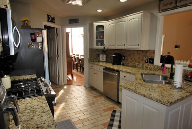 kitchen featuring light stone counters, backsplash, white cabinets, appliances with stainless steel finishes, and sink