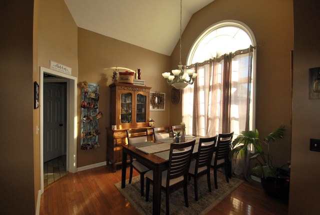 dining space featuring dark hardwood / wood-style floors, lofted ceiling, and a chandelier