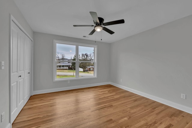 unfurnished bedroom with visible vents, a closet, light wood finished floors, baseboards, and ceiling fan