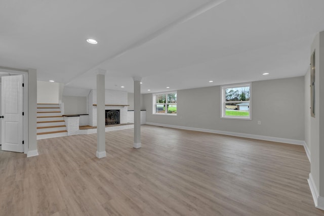 basement featuring recessed lighting, stairway, light wood-style flooring, and a brick fireplace