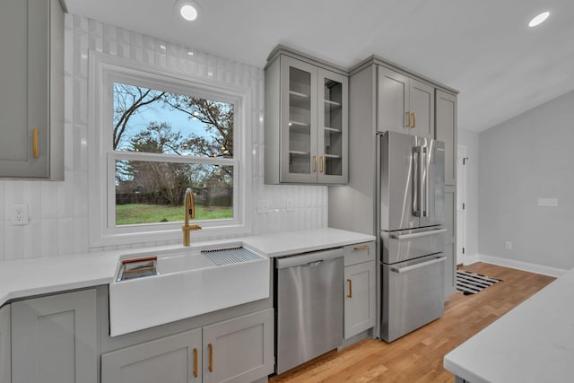 kitchen with tasteful backsplash, gray cabinets, appliances with stainless steel finishes, and a sink