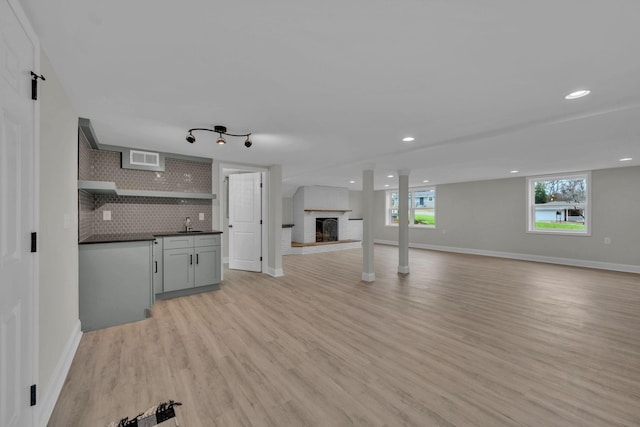 kitchen featuring dark countertops, light wood finished floors, decorative backsplash, a fireplace, and open shelves