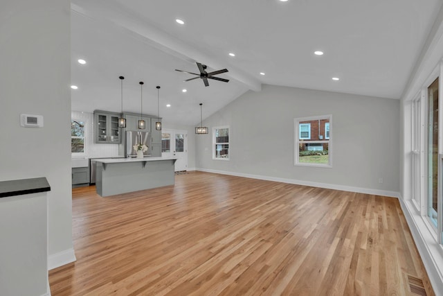 unfurnished living room with baseboards, light wood-style flooring, and vaulted ceiling with beams