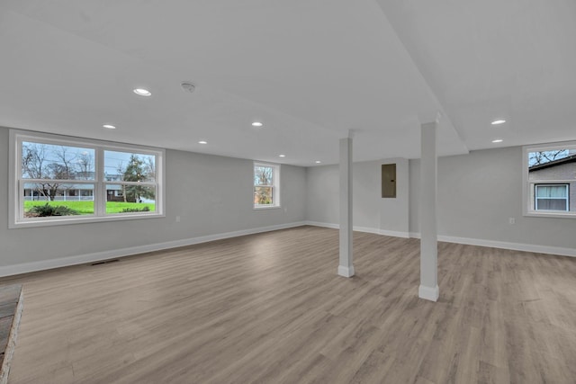 basement with wood finished floors, visible vents, baseboards, electric panel, and recessed lighting