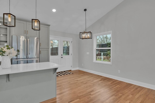 kitchen featuring vaulted ceiling, light countertops, light wood-type flooring, and freestanding refrigerator