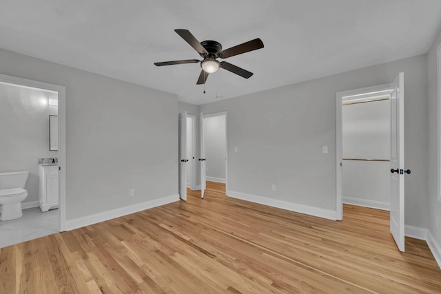 unfurnished bedroom featuring ceiling fan, baseboards, light wood-style floors, and ensuite bath