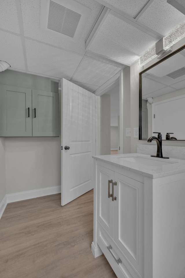 bathroom featuring visible vents, a paneled ceiling, baseboards, and wood finished floors