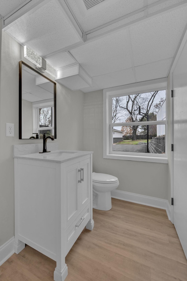 bathroom featuring toilet, vanity, baseboards, and wood finished floors