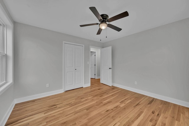 unfurnished bedroom with a closet, light wood-style flooring, and baseboards